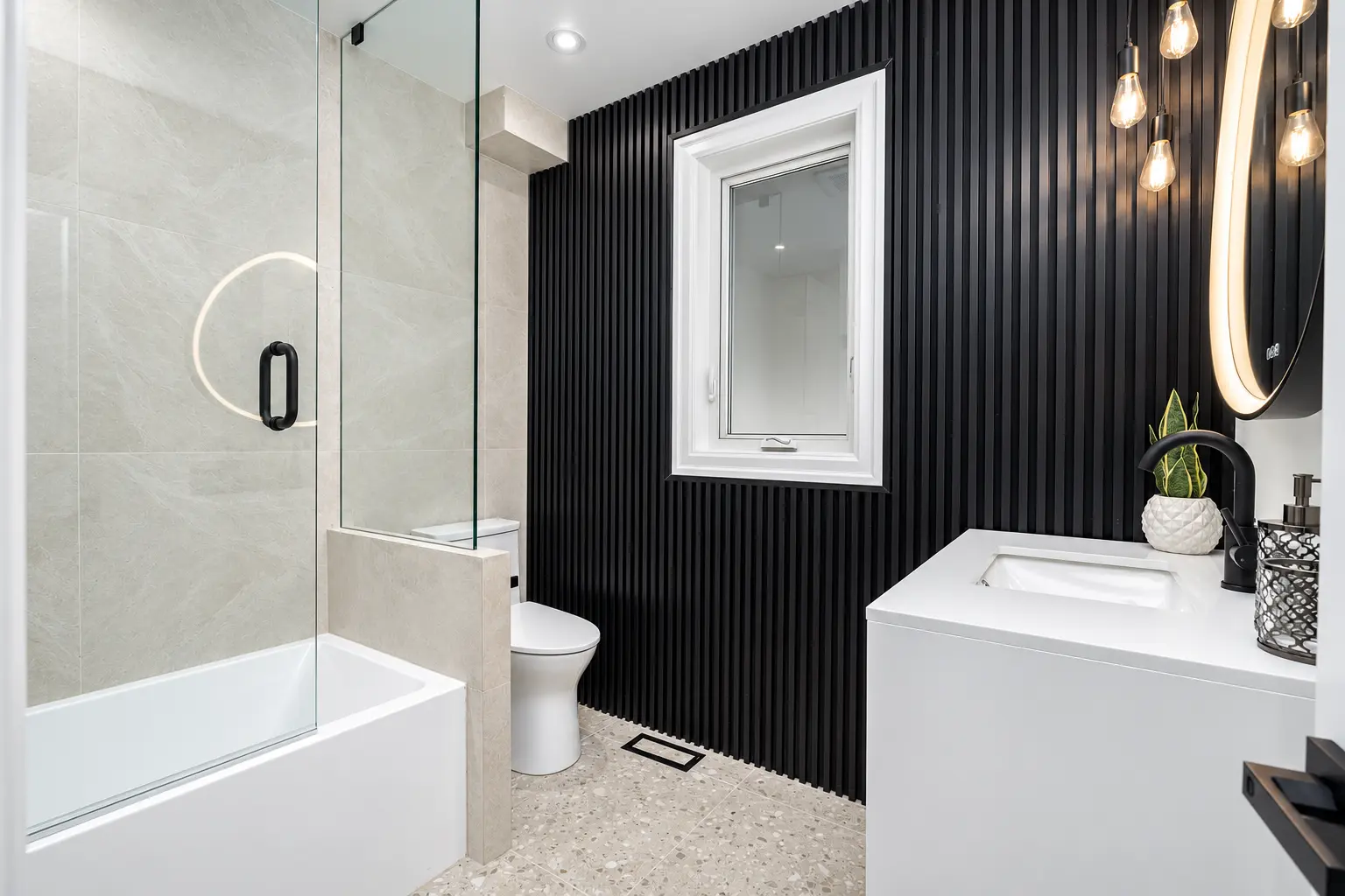 Completed bathroom with a black fluted feature wall and glass tub enclosure