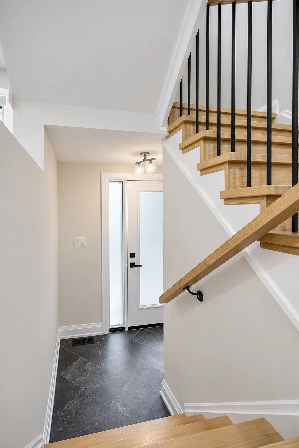 Completed bright entry and oak staircase with black metal balusters