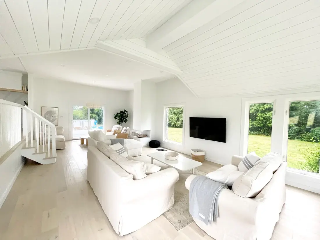 The same living room after renovation with a vaulted ceiling, opened staircase and large windows