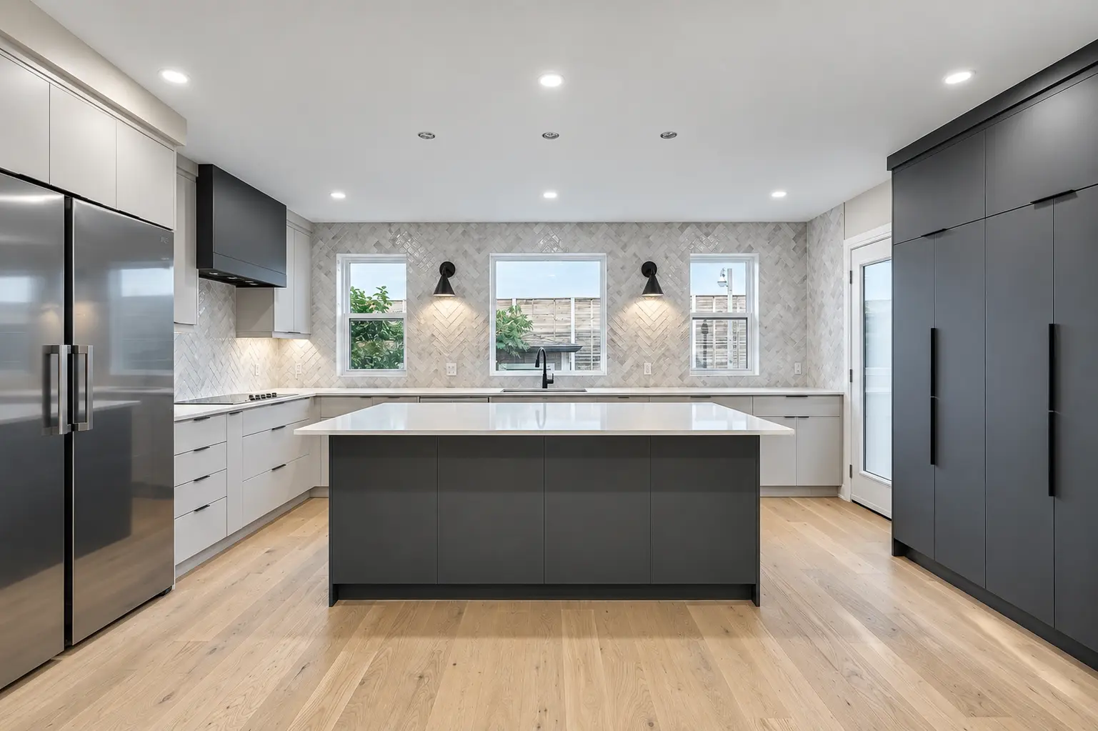 Completed open-concept main floor with custom dark cabinetry, white counters and warm wood flooring